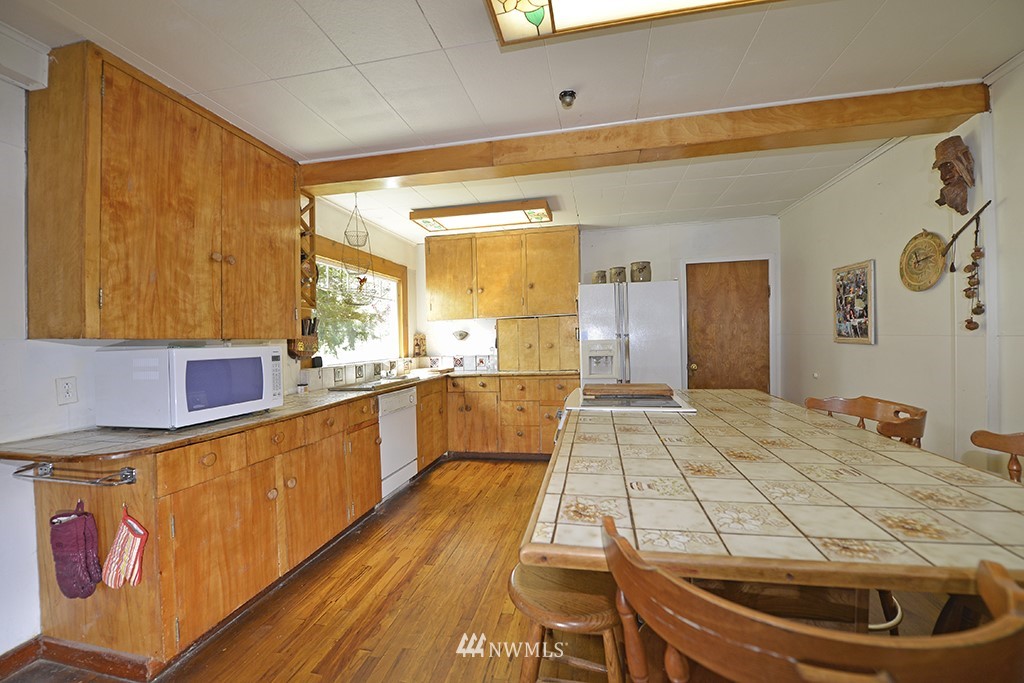 322 North End Omak Lake Road Omak, WA 98841 - Photo 27 of 40 a large kitchen with kitchen island a stove a sink dishwasher and wooden cabinets with wooden floor