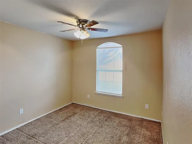 an empty room with a window and a ceiling fan
