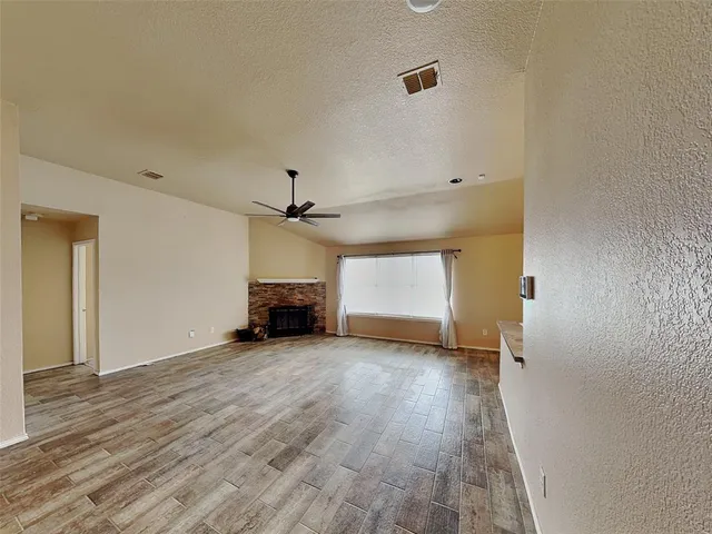 a view of empty room with wooden floor and ceiling fan