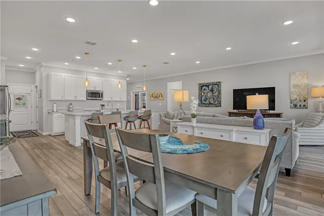 a kitchen with kitchen island granite countertop a sink a stove a refrigerator and white cabinets with wooden floor