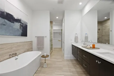 a spacious bathroom with a double vanity sink a large mirror and a bathtub