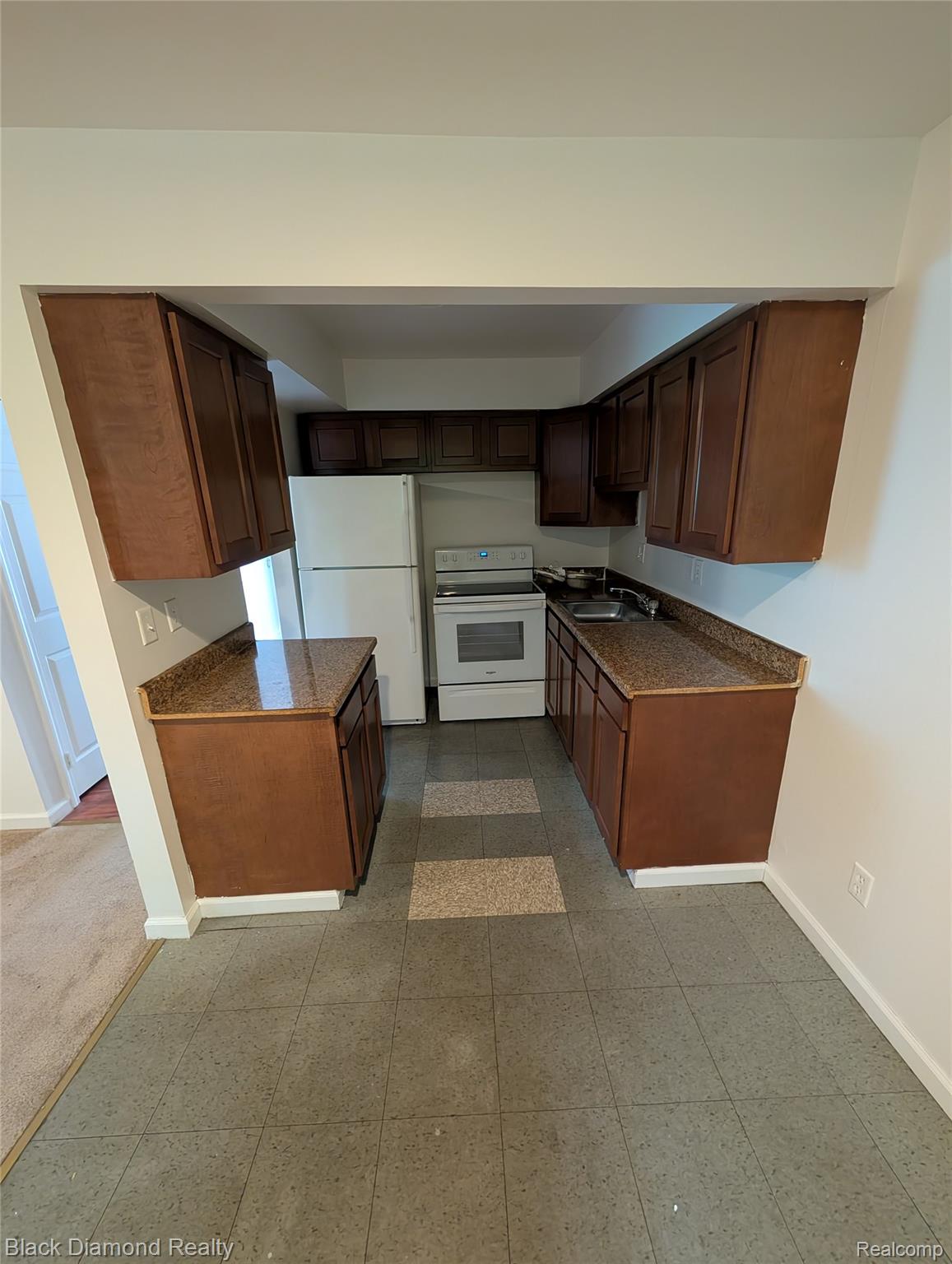 16217 Greenfield Road Detroit, MI 48235 - Photo 9 of 16 Galley kitchen featuring dark wood-finish cabinetry, speckled countertops, a white refrigerator, and a white electric range