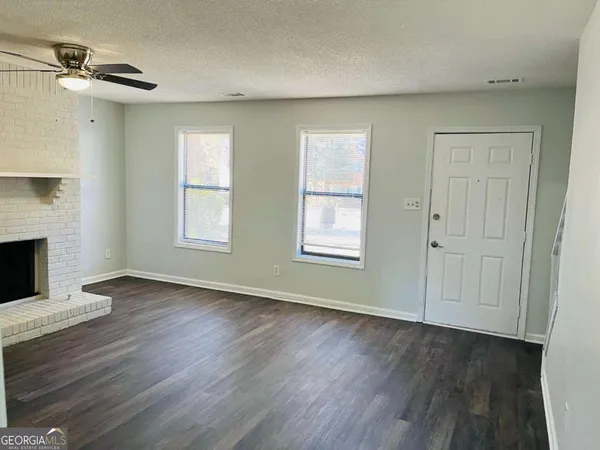 an empty room with wooden floor fireplace and windows