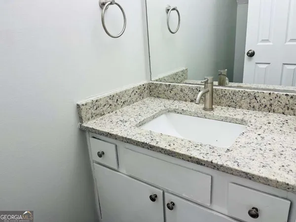 a bathroom with a granite countertop sink and a mirror