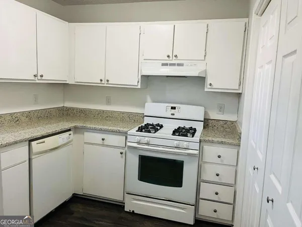 a kitchen with granite countertop white cabinets and white appliances