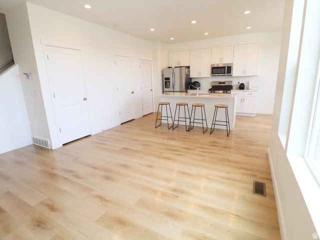 8240 Cascade Vw Way Magna, UT 84044 - Photo 2 of 18 Kitchen featuring a breakfast bar area, stainless steel appliances, light wood-style flooring, a kitchen island with sink, and recessed lighting