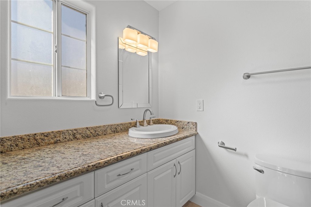 14957 Victory Boulevard, Unit 101 Van Nuys, CA 91411 - Photo 15 of 26 a bathroom with a granite countertop sink and a mirror