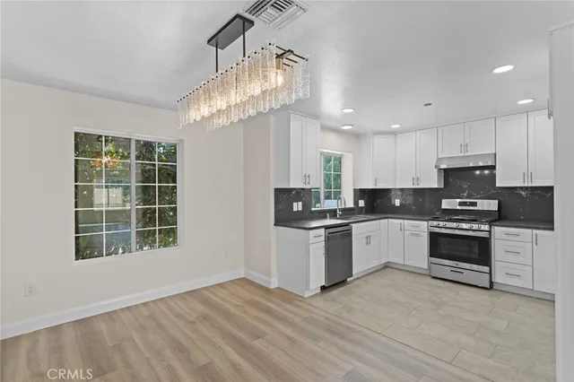 a kitchen with granite countertop a stove a sink and a refrigerator
