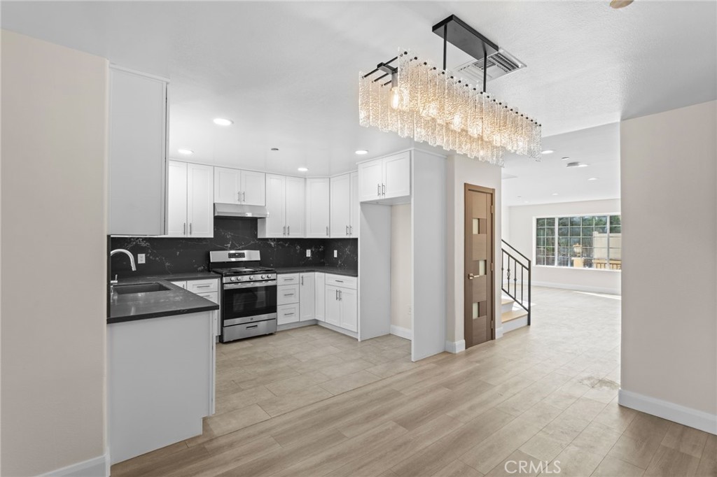 14957 Victory Boulevard, Unit 101 Van Nuys, CA 91411 - Photo 6 of 26 a kitchen with stainless steel appliances granite countertop a refrigerator a sink dishwasher a stove and white cabinets with wooden floor