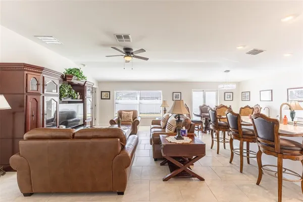 a large kitchen with stainless steel appliances lots of white furniture a refrigerator a stove a dining table and chairs with wooden floor