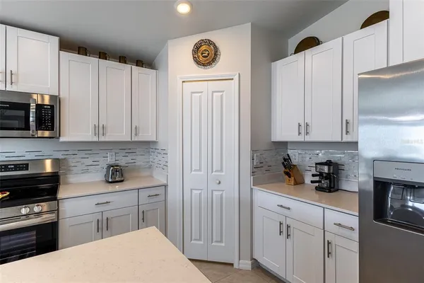a kitchen with stainless steel appliances granite countertop a sink a stove a refrigerator and white cabinets
