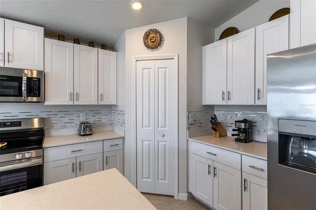 a kitchen with stainless steel appliances granite countertop a sink a stove a refrigerator and white cabinets