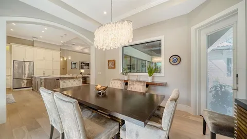 a dining room with wooden floor a chandelier a wooden table and chairs
