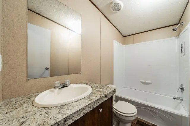 a bathroom with a granite countertop sink toilet a mirror and shower