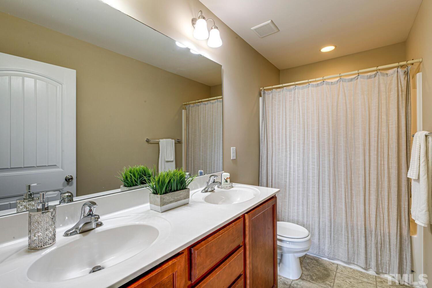 2416 Savior Street Raleigh, NC 27610 - Photo 28 of 47 a bathroom with a double vanity sink toilet and a mirror