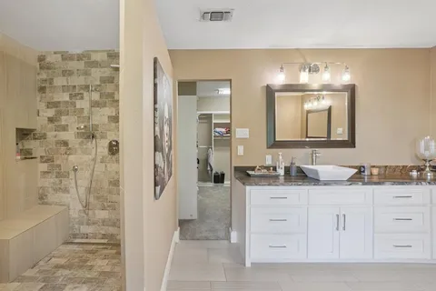 a bathroom with a double vanity sink a mirror a bathtub and shower