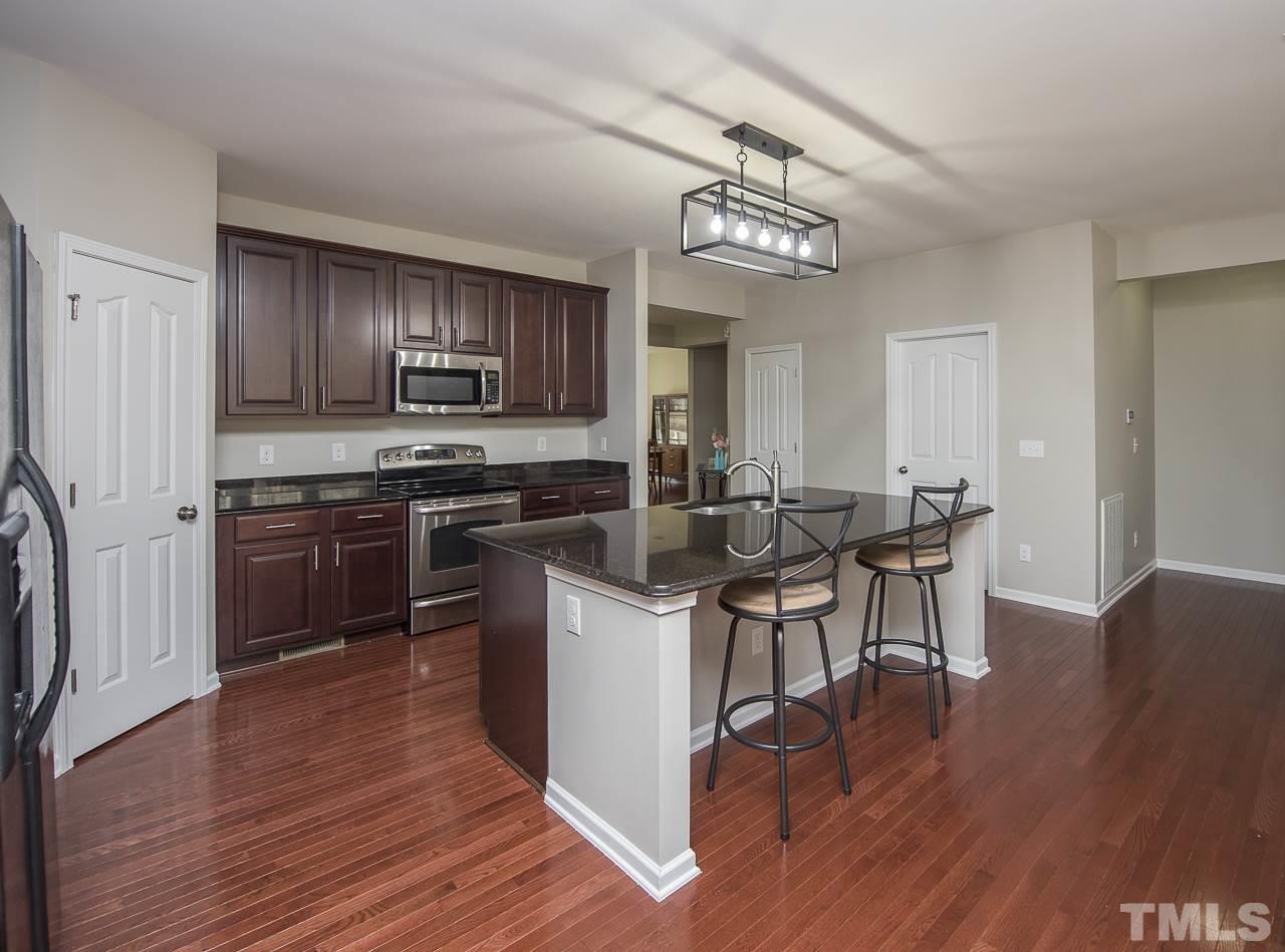 1136 Farmers Branch Road Willow Spring, NC 27592 - Photo 6 of 30 a kitchen with stainless steel appliances a table chairs sink and cabinets