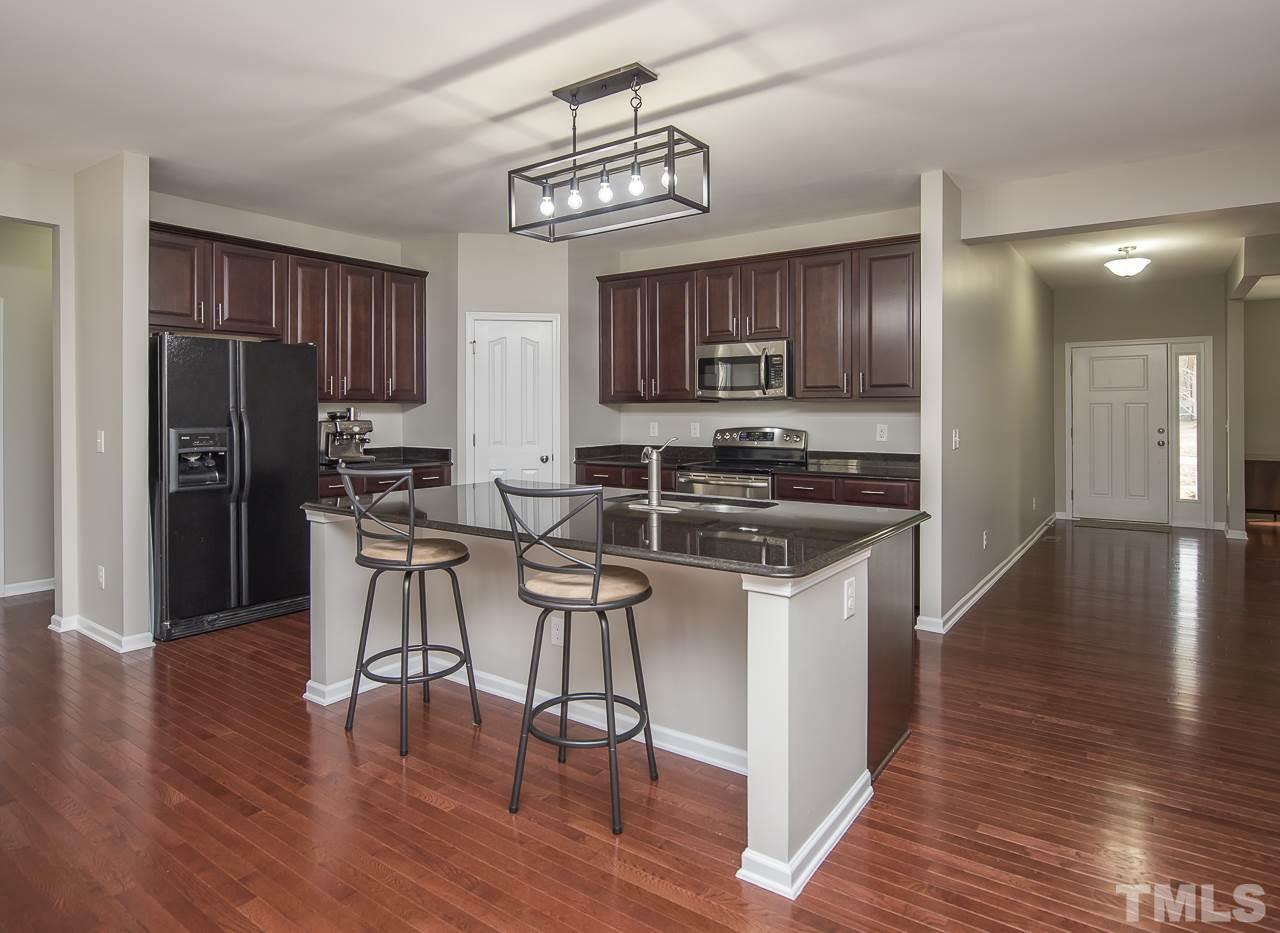 1136 Farmers Branch Road Willow Spring, NC 27592 - Photo 7 of 30 a kitchen with stainless steel appliances a stove top oven a refrigerator a sink and a dining table with wooden floor