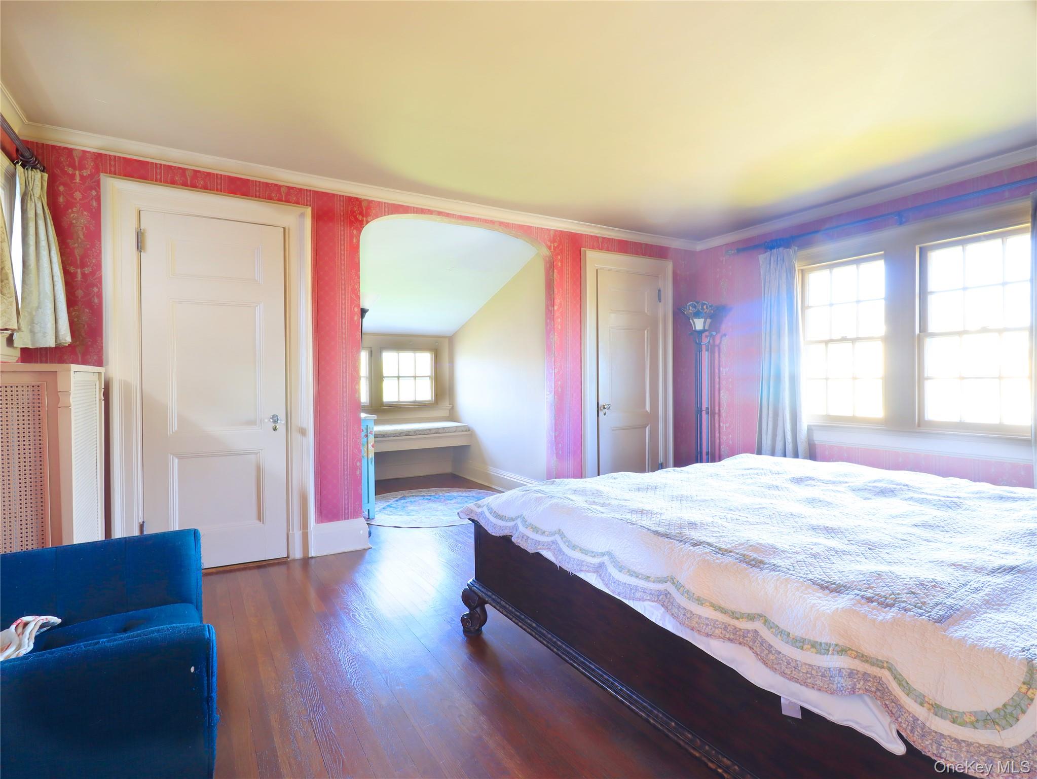 11-20 Shore Road Queens, NY 11363 - Photo 39 of 45 Hardwood flooring in a bright room with patterned wall covering, multiple windows, and a coved entryway to an additional space featuring a built-in window seat