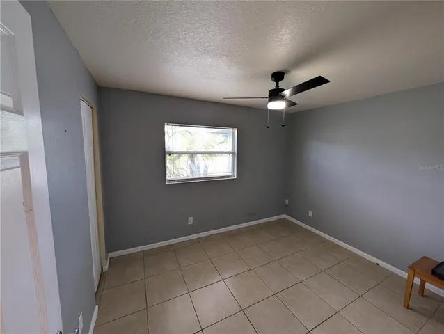 an empty room with windows and ceiling fan