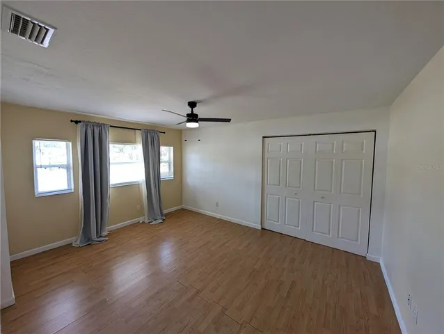 an empty room with wooden floor and windows