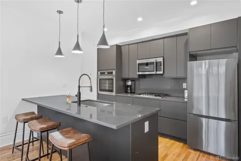 a kitchen with stainless steel appliances granite countertop a sink a microwave a refrigerator and wooden cabinets