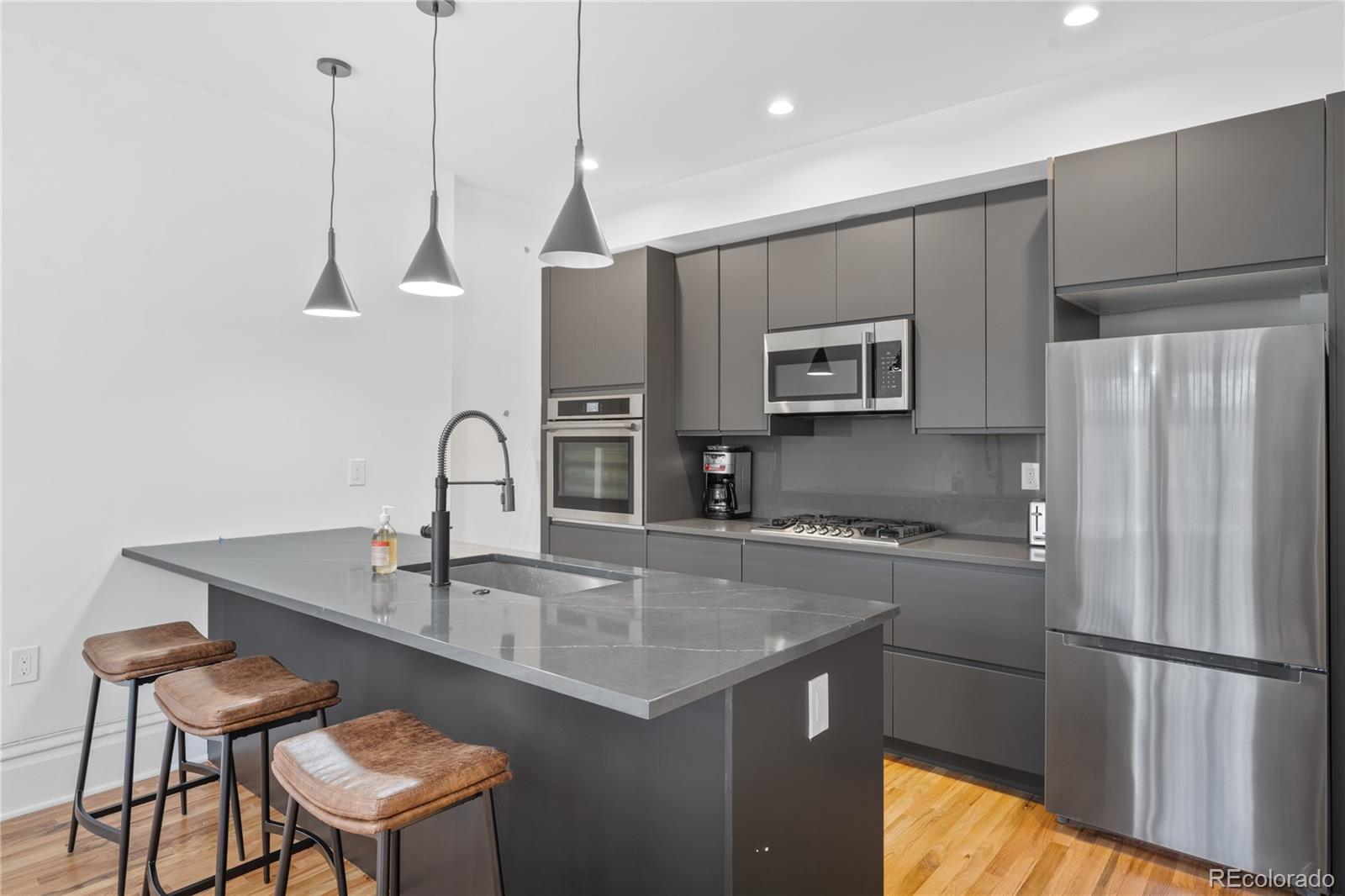 1442-1444 Stuart Street Denver, CO 80204 - Photo 13 of 26 a kitchen with stainless steel appliances granite countertop a sink a microwave a refrigerator and wooden cabinets