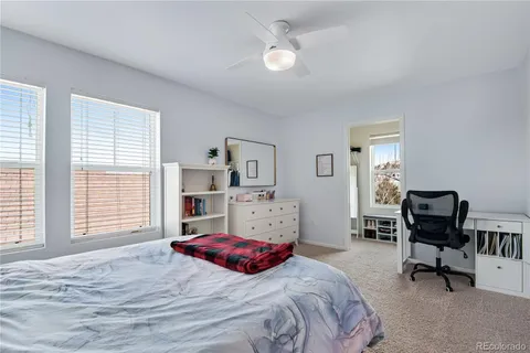 a bed sitting in a bedroom next to a window and a larger window