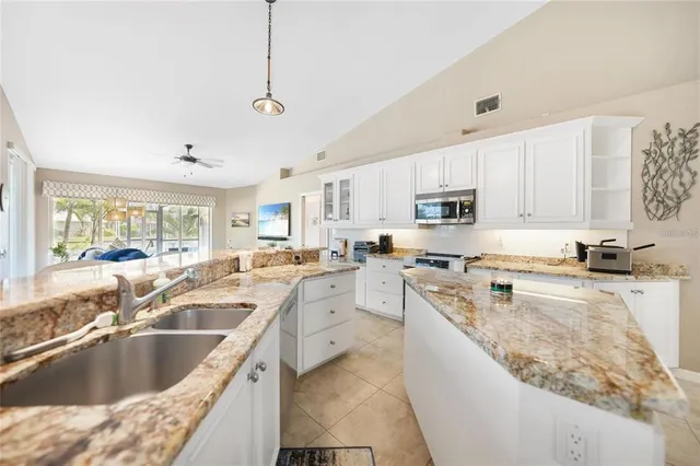 a large kitchen with stainless steel appliances granite countertop a sink stove and refrigerator