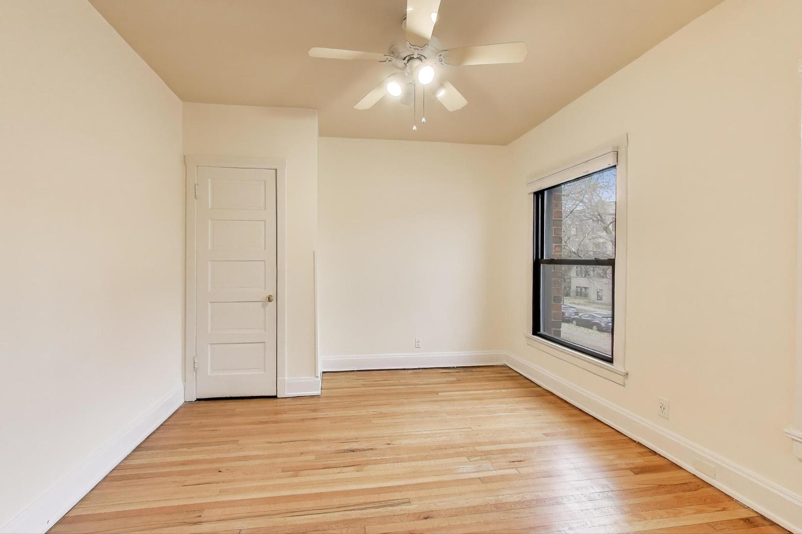 847 Judson Avenue, Unit 2 Evanston, IL 60202 - Photo 7 of 19 an empty room with wooden floor chandelier fan and windows