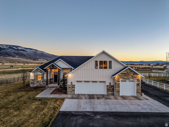 Modern inspired farmhouse featuring board and batten siding, stone siding, and concrete driveway