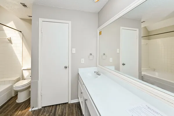 a spacious bathroom with a bathtub shower sink mirror and toilet