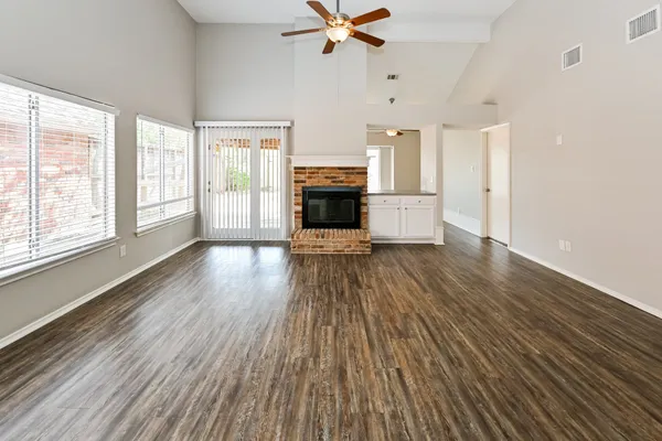 an empty room with wooden floor fireplace and windows