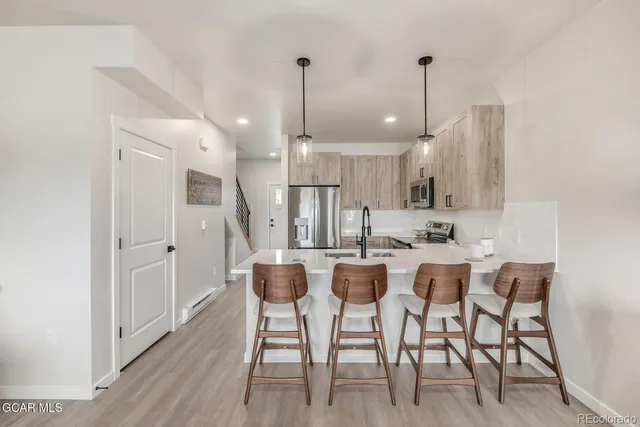 a kitchen with a sink dishwasher and white cabinets with wooden floor