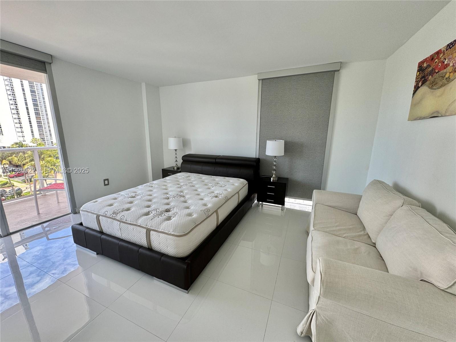 3731 North Country Club Drive, Unit 623 Aventura, FL 33180 - Photo 17 of 30 a bedroom with a bed lamp and a large window