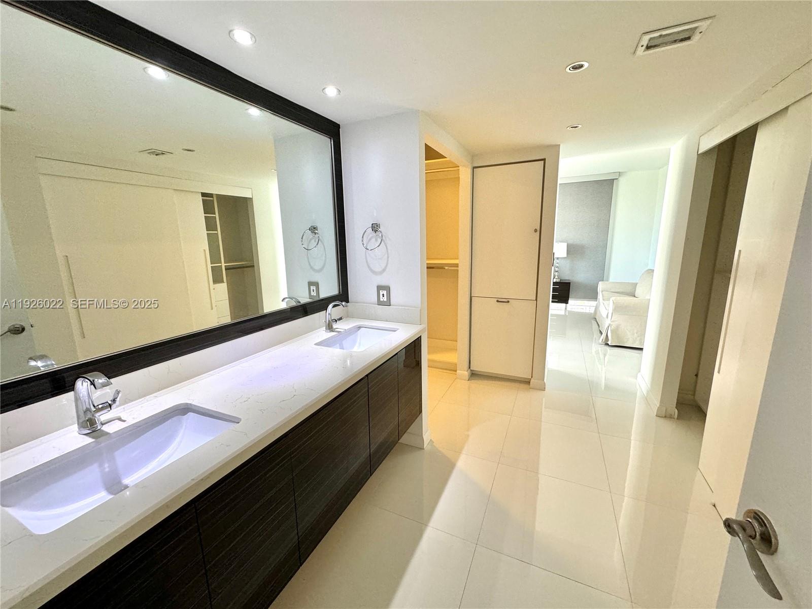 3731 North Country Club Drive, Unit 623 Aventura, FL 33180 - Photo 19 of 30 a bathroom with a double vanity sink a mirror and a shower