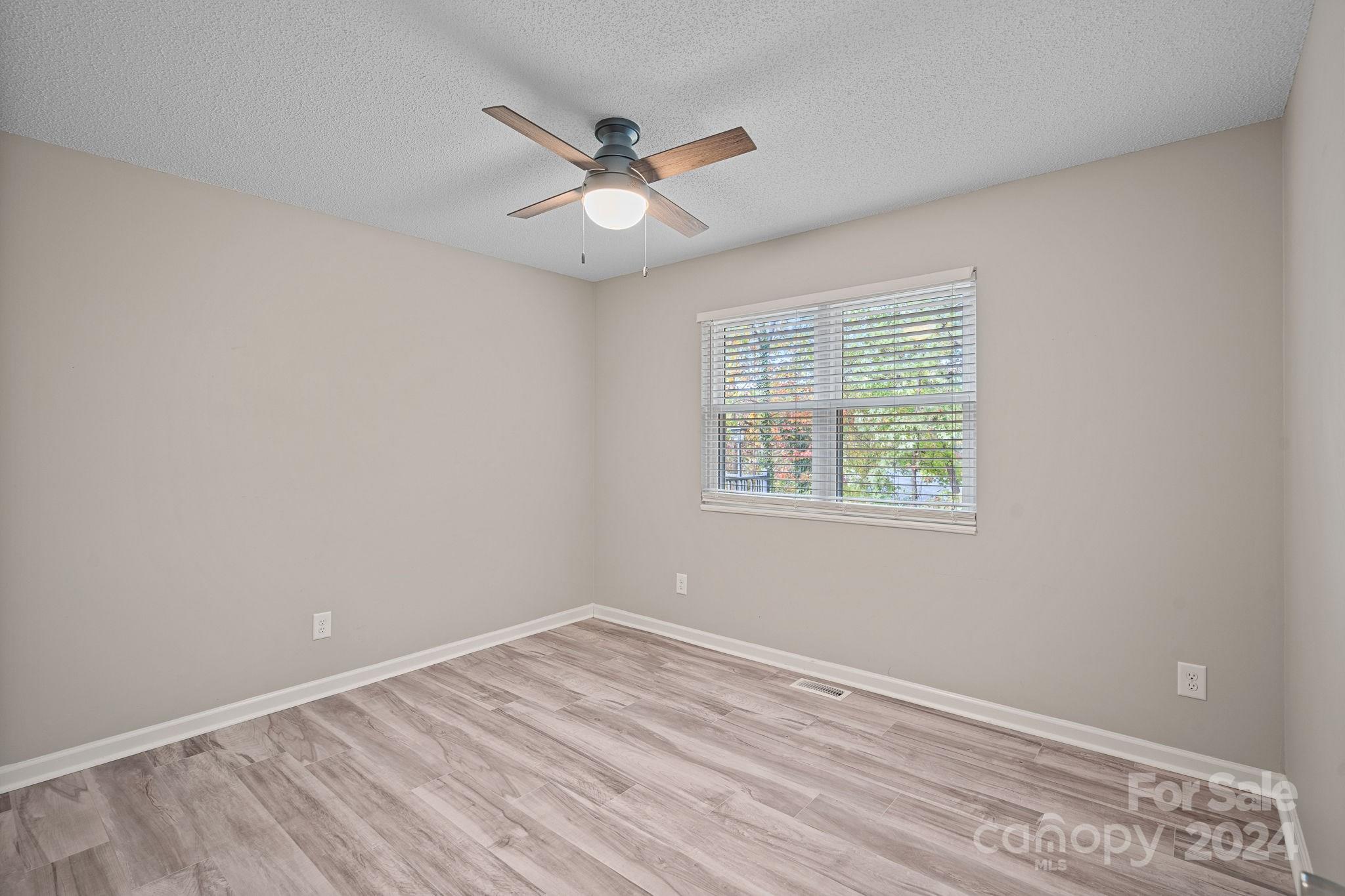 7505 Sarah Drive Denver, NC 28037 - Photo 12 of 34 an empty room with wooden floor fan and windows