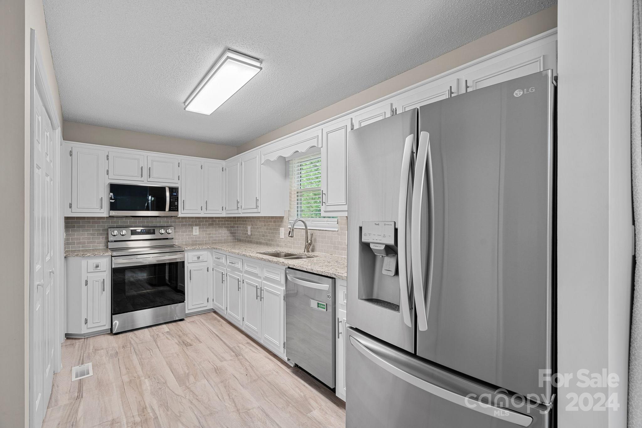 7505 Sarah Drive Denver, NC 28037 - Photo 7 of 34 a kitchen with stainless steel appliances a refrigerator sink and microwave