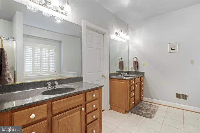 a bathroom with a granite countertop double vanity sink a mirror and a window