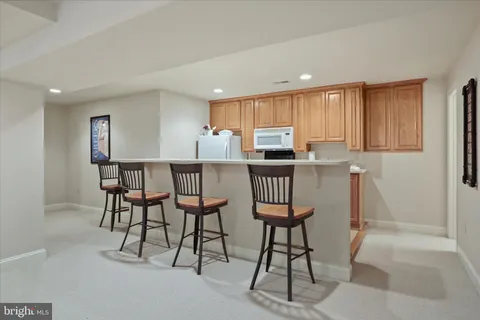 a kitchen with stainless steel appliances kitchen island a table chairs in it and white cabinets