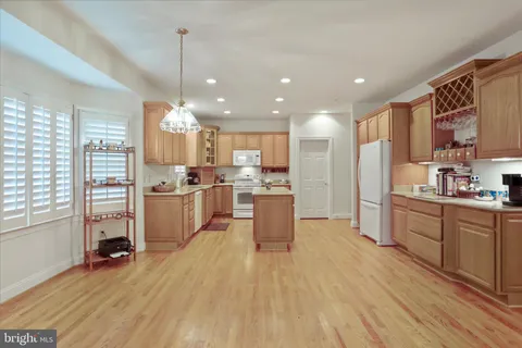 a kitchen with stainless steel appliances kitchen island granite countertop a refrigerator a oven a sink and white cabinets with wooden floor