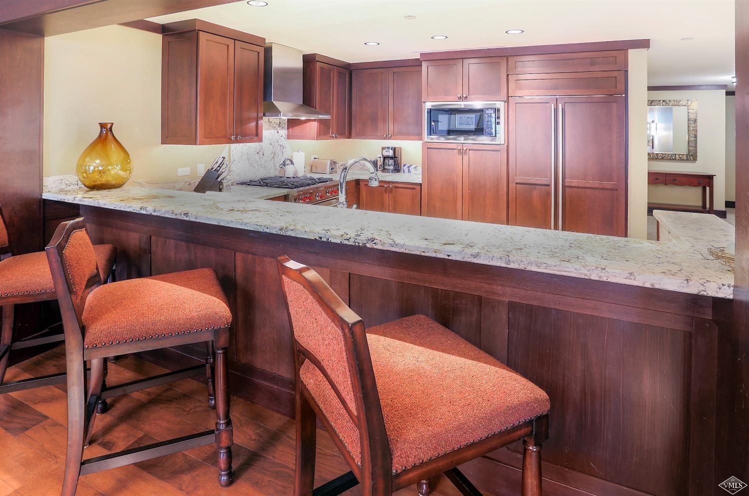 1 Vail Road, Unit 4103 Vail, CO 81657 - Photo 7 of 19 a kitchen with granite countertop chair and wooden cabinets