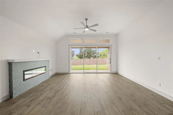 an empty room with wooden floor chandelier and windows