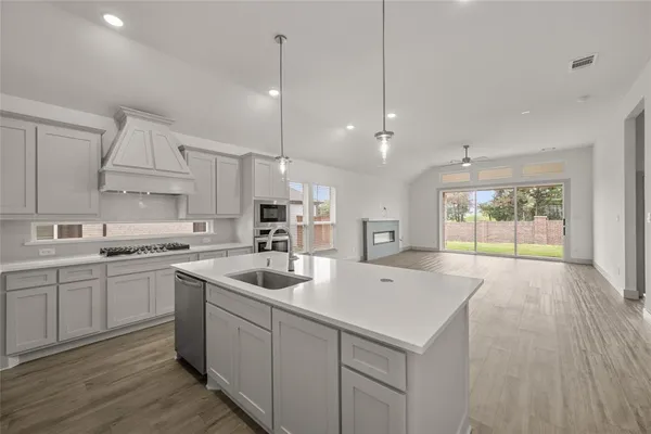 a kitchen with sink stove and white cabinets with wooden floor