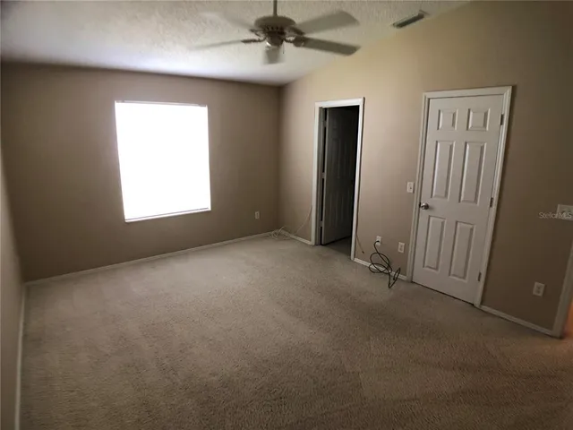 an empty room with windows and fan