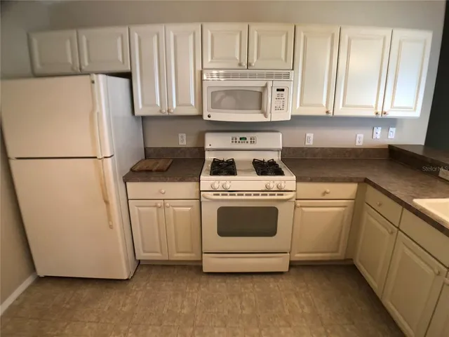 a white refrigerator freezer and a stove sitting inside of a kitchen