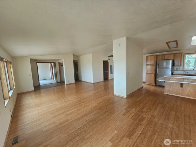 a view of a big room with wooden floor and a kitchen