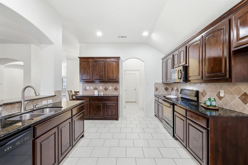 3818 Downing Drive Midlothian, TX 76065 - Photo 5 of 32 Kitchen featuring dark stone counters, black appliances, dark wood finish cabinets, vaulted ceiling, and arched walkways