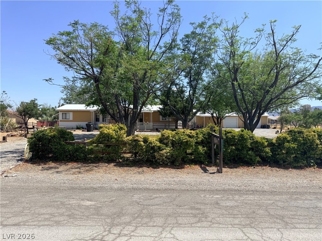 1391 West Dyer Road Pahrump, NV 89048 - Photo 8 of 50 An inviting exterior with ample frontage features lush trees, offering natural shade and curb appeal.