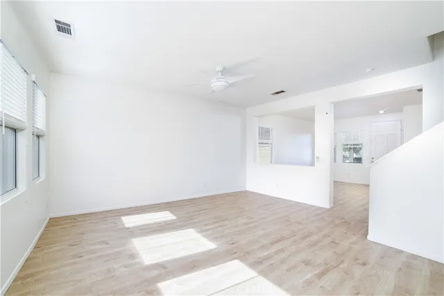 a view of an empty room with wooden floor and a kitchen